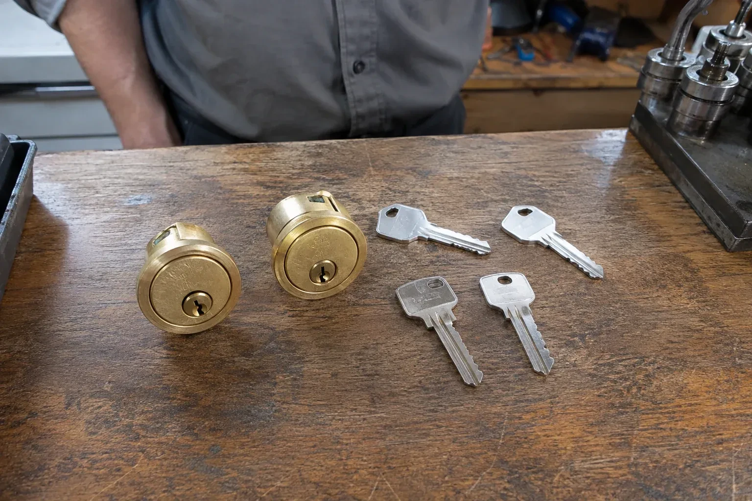 Two detached brass lock cylinders and four house keys on a wooden counter. — Lock Rekeying, Woodstock